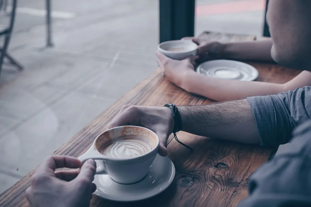 カウンターでコーヒーカップを持つ二人の手元