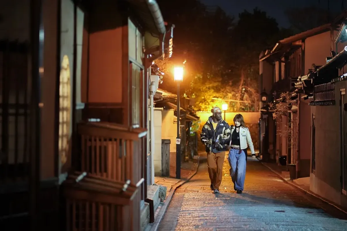 街灯に照らされた夜の石畳の路地を、少し間を空けて並んで歩く男女