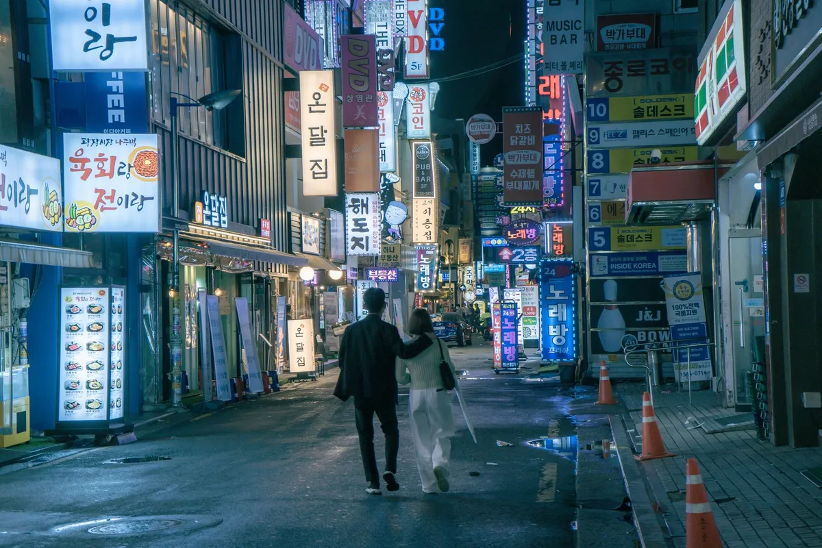 夜の繁華街を足早に歩く人の後ろ姿