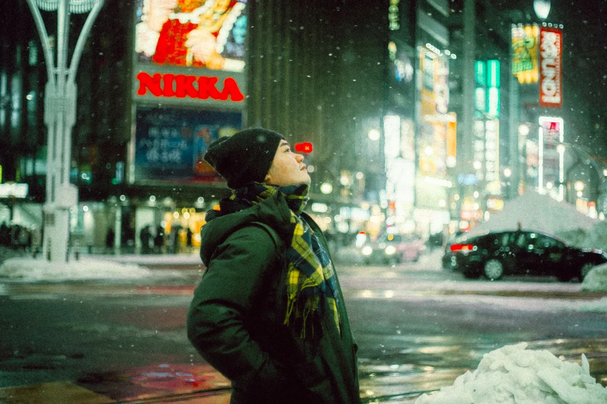 雪の降る街路で立ち止まっている人