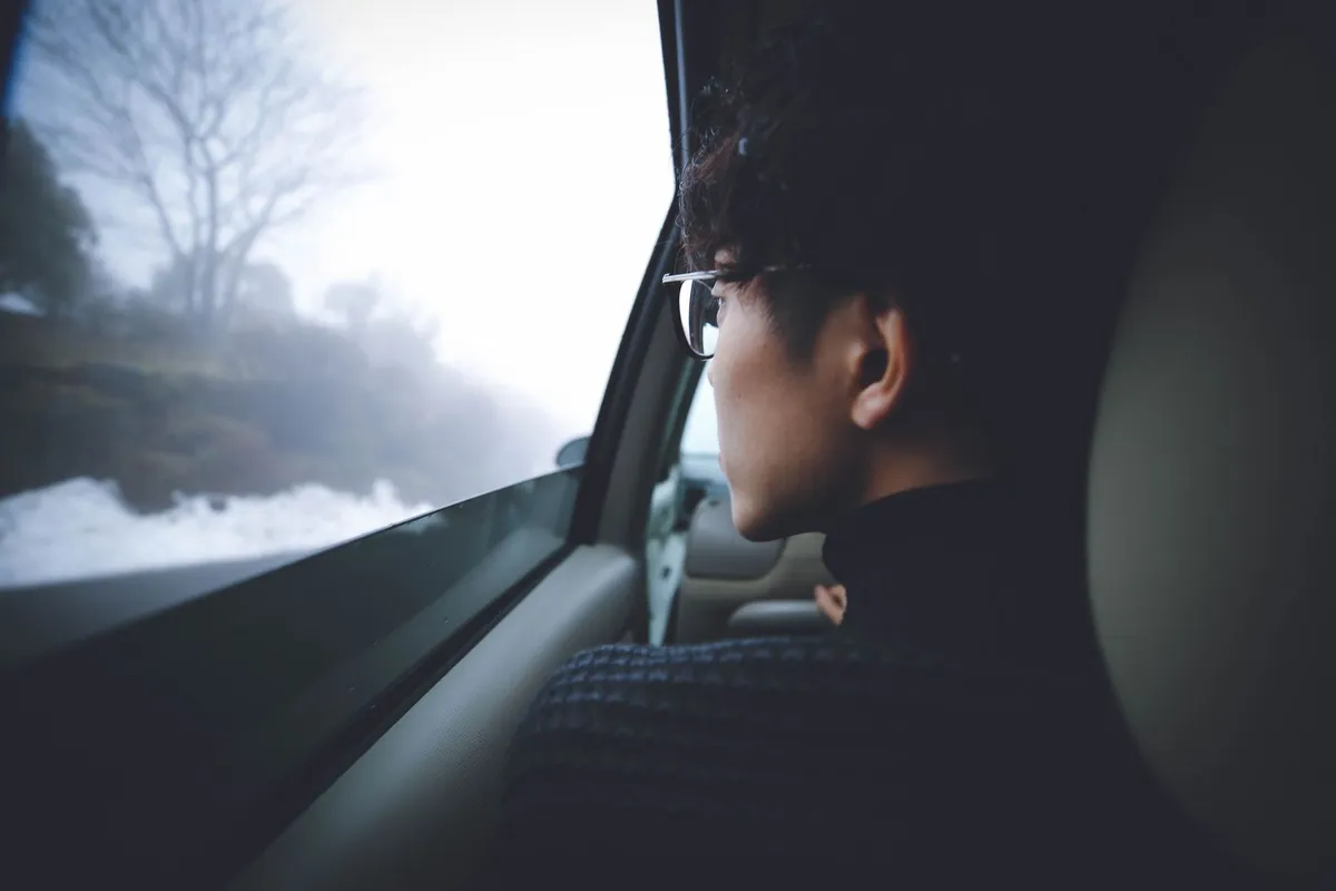 電車の窓の外を眺めて考えごとをする人